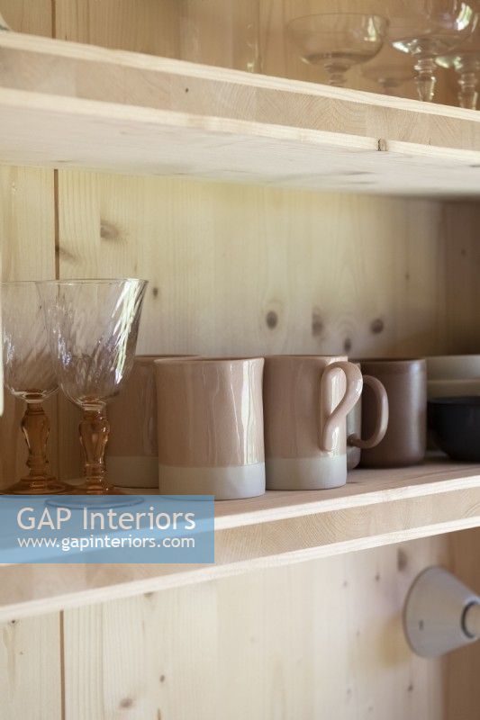 Détail de la verrerie et des tasses sur une étagère de cuisine en bois