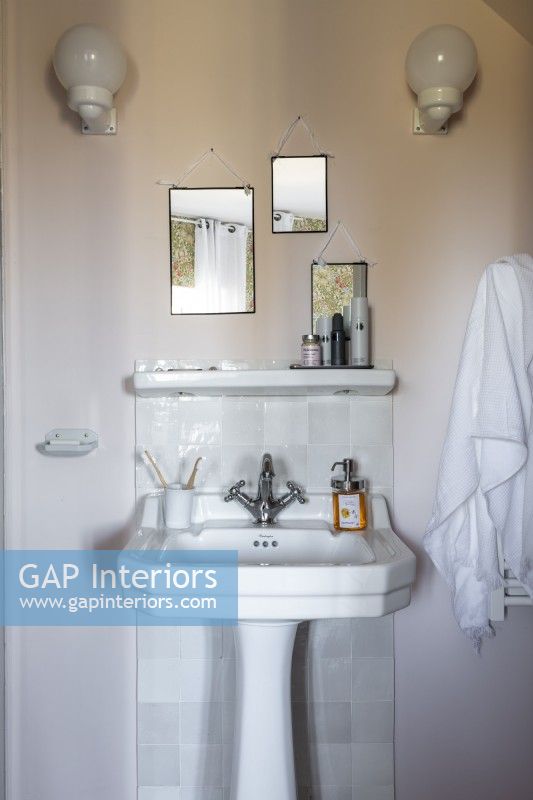 Lavabo de style classique dans la salle de bain avec trois miroirs sur le mur au-dessus