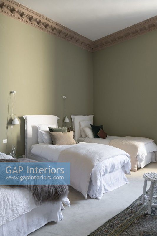 Trois lits simples dans une chambre aux murs peints en vert