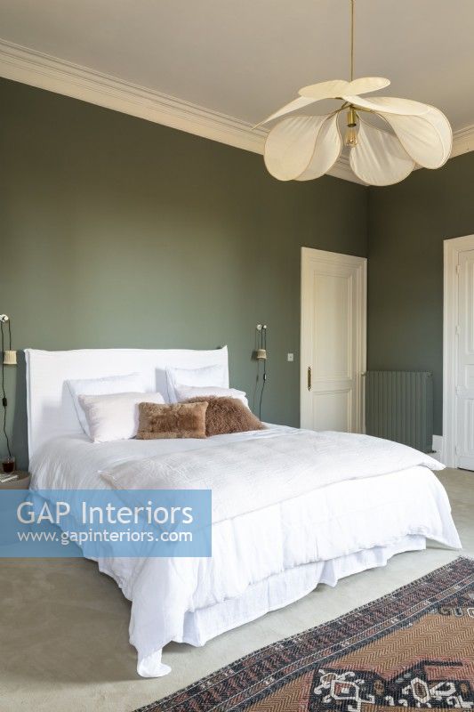 Chambre de style classique avec murs peints en vert et literie blanche