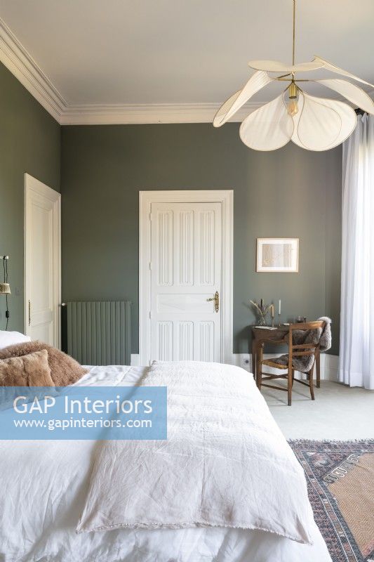 Chambre avec murs peints en vert et literie blanche