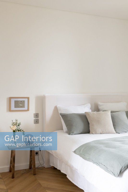 Chambre blanche simple avec coussins et couvre-lit gris pâle