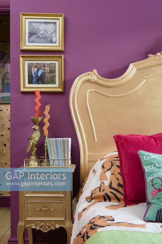 Lit français peint en or et table d'appoint dans une chambre rose
