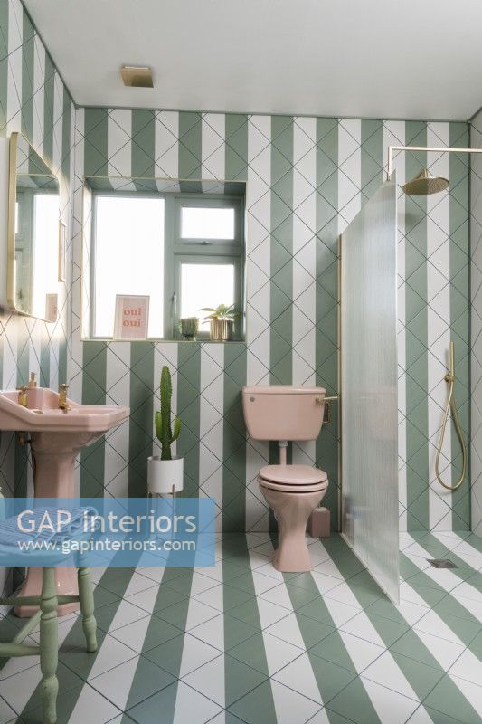 Salle de bains carrelée à rayures vertes et blanches avec sanitaires roses