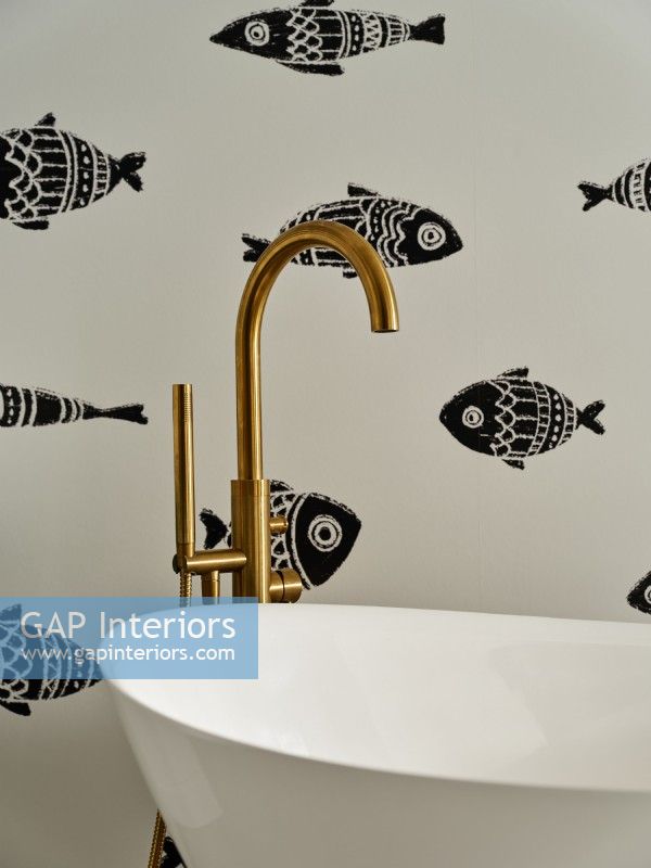 Détail de la baignoire avec robinet doré et papier peint à motifs de poissons