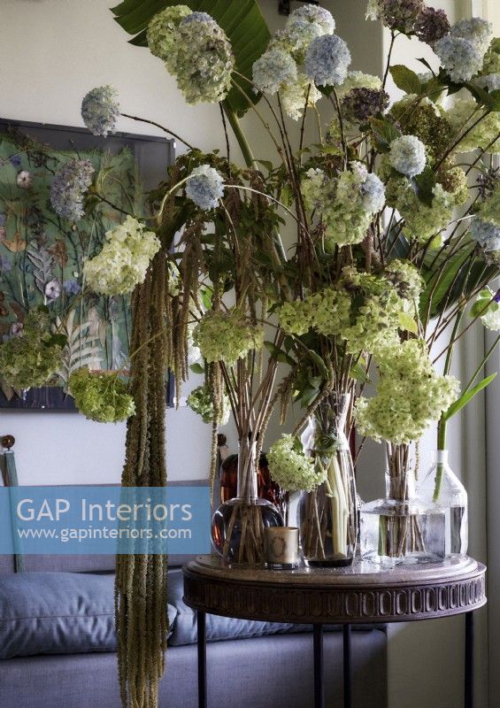 Grand écran de fleurs dans des vases sur une petite table ronde en bois