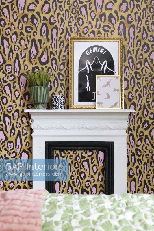 Un foyer et une cheminée blancs et noirs contre un mur recouvert de papier peint à imprimé léopard