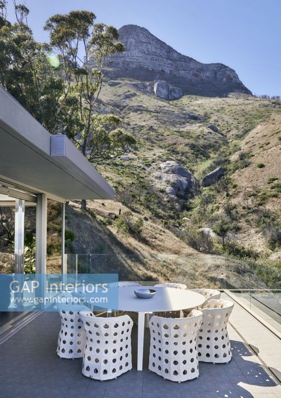 Table et chaises blanches sur terrasse avec vue sur les montagnes