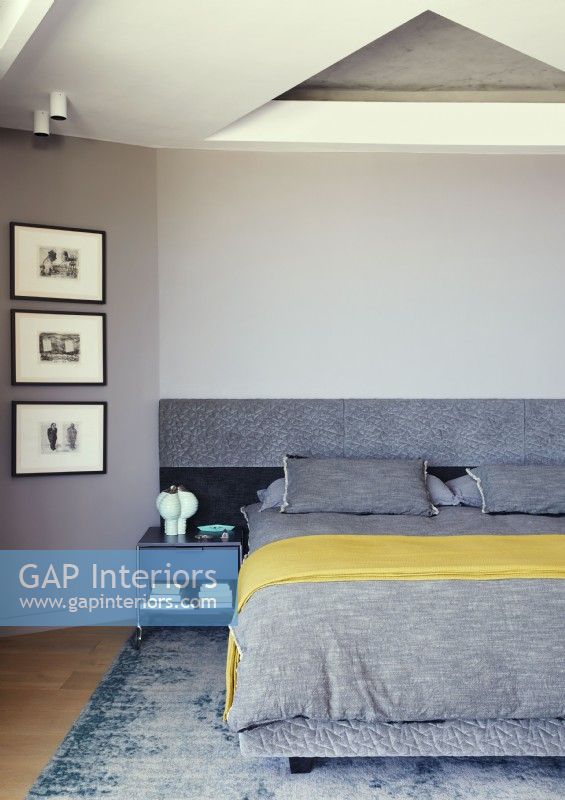 Literie grise et jaune sur le lit dans la chambre moderne