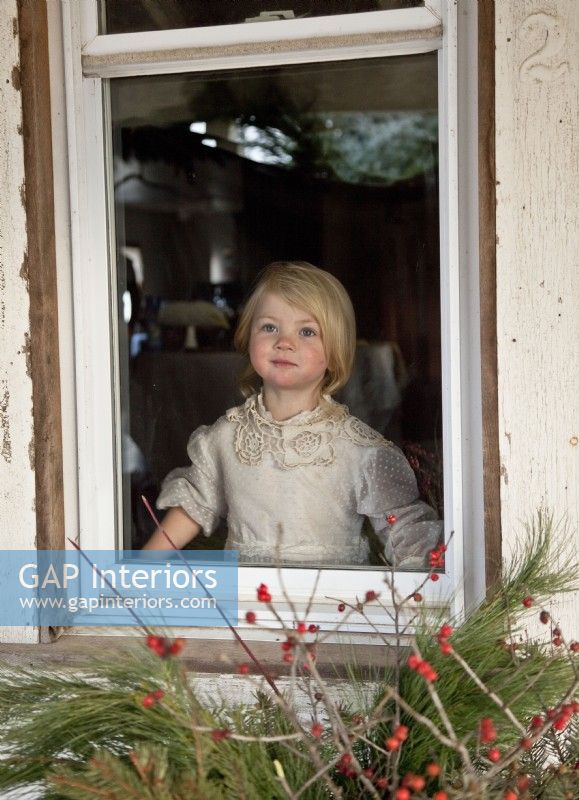 Petite fille portant une robe vintage regardant le Père Noël depuis une fenêtre