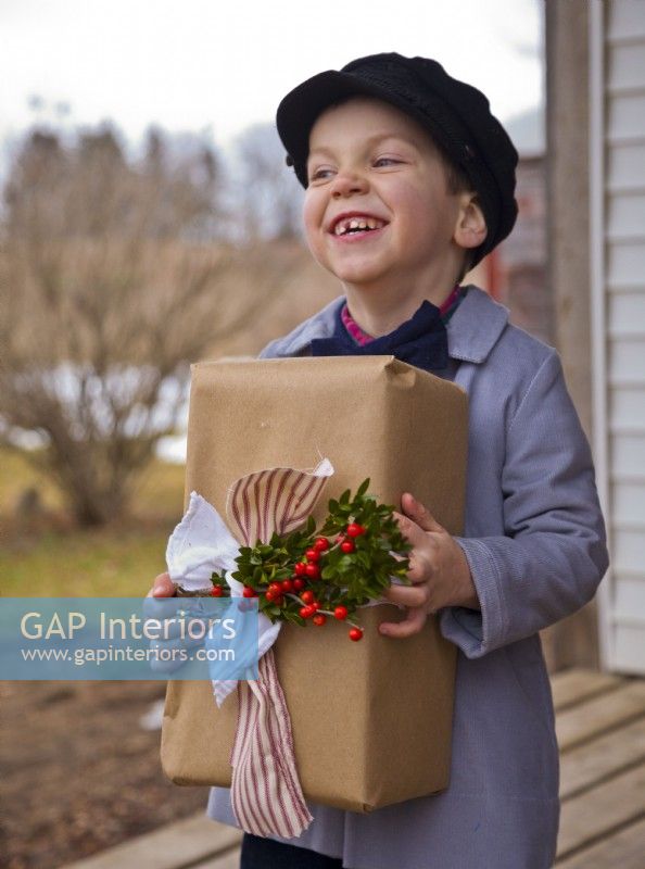 Petit garçon avec béret tenant un cadeau de Noël emballé et décoré