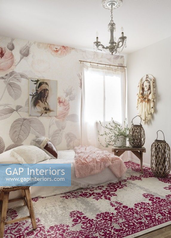 Un papier peint à motif de roses, un attrape-rêves et un tapis de style tapisserie apportent une ambiance bohème romantique à la chambre d'amis.a