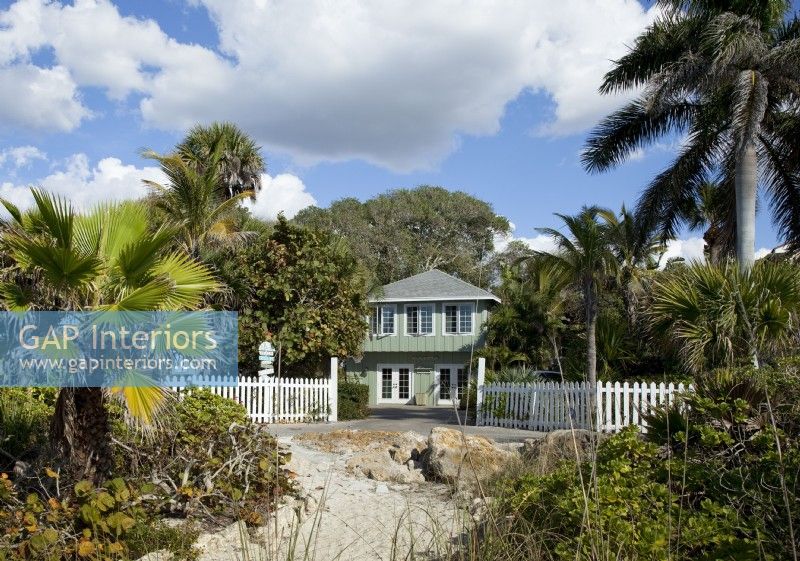 L'extérieur du cottage vintage classique de Floride a été peint en vert pâle avec des garnitures blanches contrastantes pour refléter le feuillage local et la plage de sable.