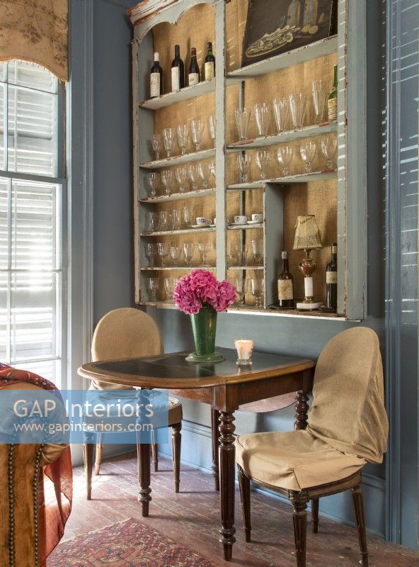 Dans un coin du salon, Renee crée l'ambiance d'un élégant café parisien avec un mur bordé de verre à vin, une table élégante et des chaises habillées.