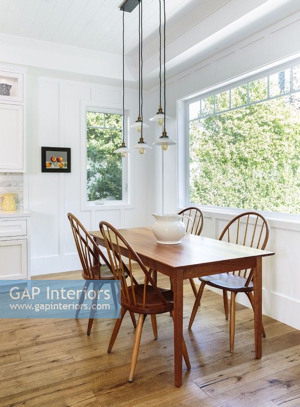 La salle à manger de la cuisine brille par la simplicité des anciennes chaises Windsor et de la table Shaker. Le quatuor de suspensions légères a une sensation vintage avec une touche moderne.