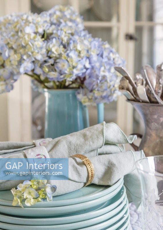 Une palette de bleus poussiéreux introduit une couleur douce dans la décoration de la table. Les serviettes en lin vintage complètent le look élégant.