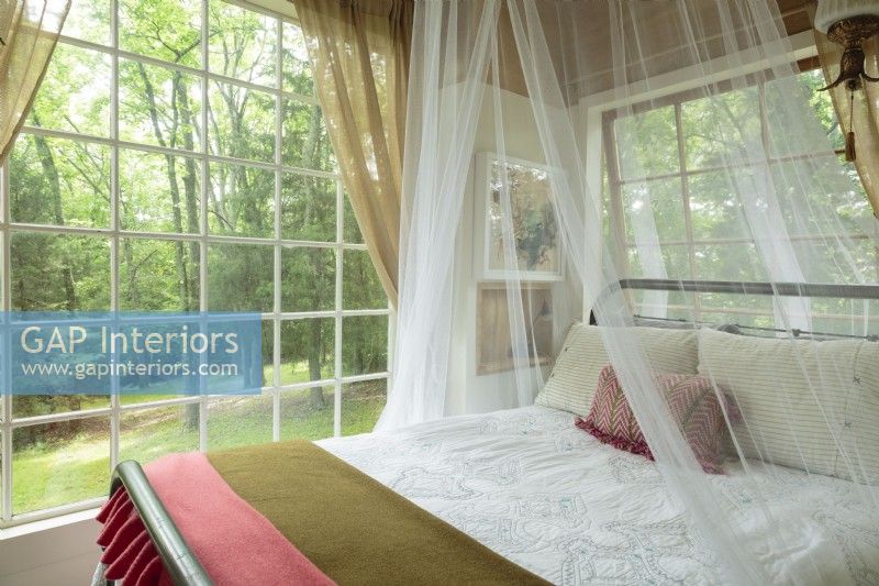 Il est facile de rêver sur le lit en fer antique et de se connecter aux rythmes de la Terre à travers les grandes fenêtres. La canopée transparente ajoute au romantisme du décor.