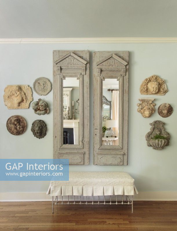 Dans le couloir, une paire de miroirs antiques est flanquée d'objets en pierre galbés et bien dimensionnés affichés dans un souci d'équilibre.
