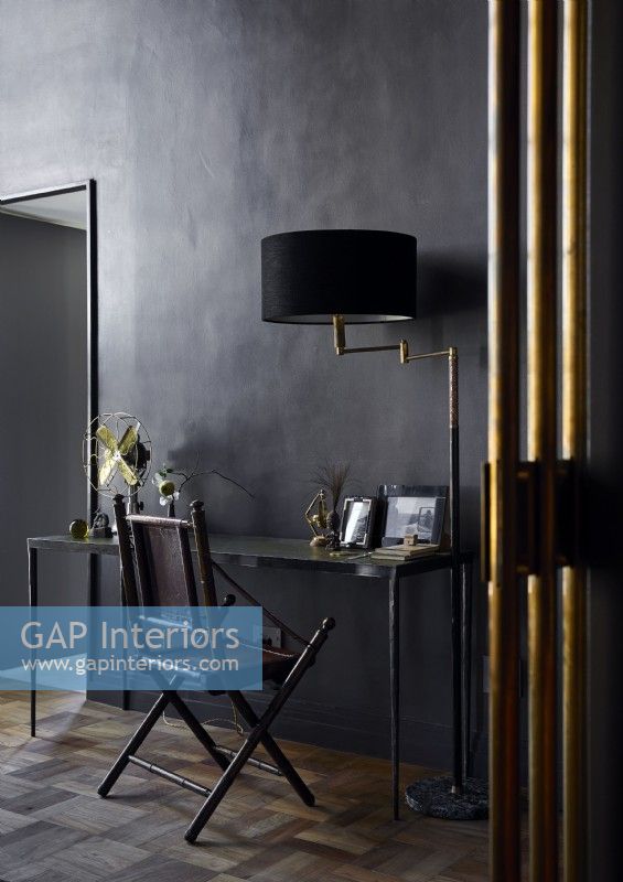Bureau et chaise classiques avec murs peints en noir et accessoires dorés