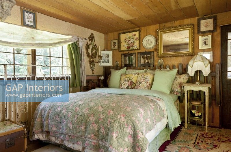 Des meubles robustes et pré-aimés et des tissus floraux féminins allient primitif et joli dans la chambre d'amis confortable. Des couches de couettes et d'oreillers donnent au lit invitant une sensation de nid.