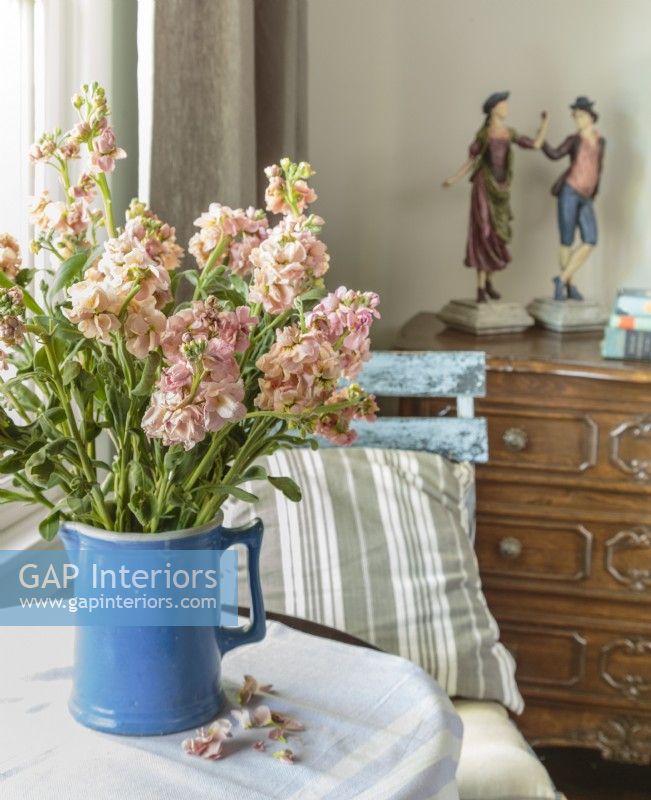 Une chaise de jardin et un pichet de fleurs apportent une saveur extérieure à la chambre.