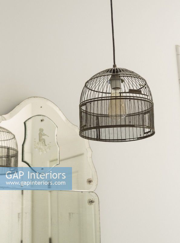 Une vieille cage à oiseaux est câblée dans le luminaire de la salle de bain.