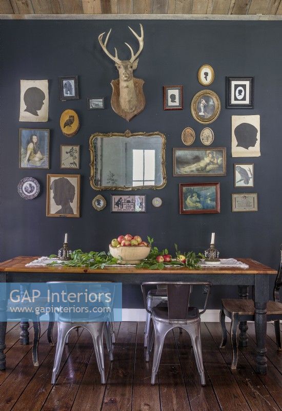 Un mur d'accent peint en gris foncé désigne une salle à manger dans l'espace ouvert tout en offrant une vitrine spectaculaire pour les objets de famille assortis et une monture de cerf vintage.