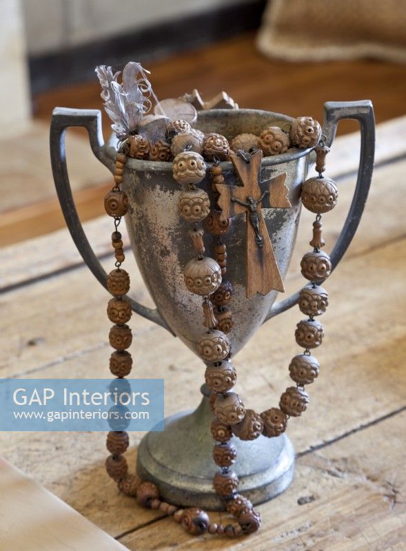Des perles de chapelet en bois sculpté surdimensionnées débordent d'une tasse d'amour ternie.