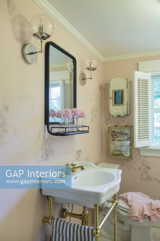 Le papier peint rose moucheté d'or habille la petite salle de bain