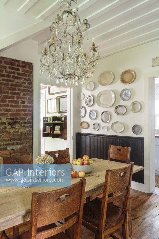 A rustic brick walls and a pine farmhouse table paired with antique schoolhouse chairs.
