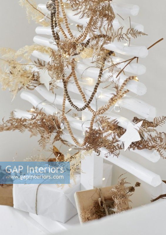 Feuilles de fougère séchées sur des décorations de perles sur l'arbre de Noël blanc