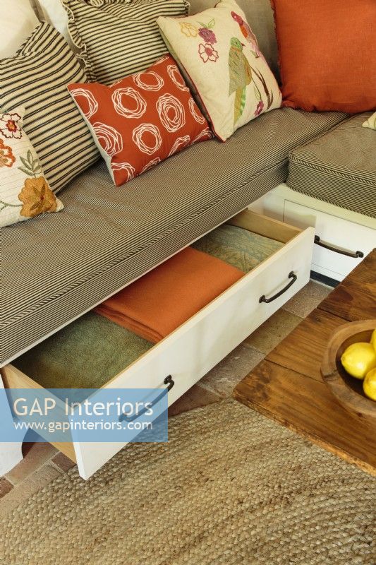 Sous le canapé, des tiroirs offrent un espace de rangement pour les draps frais et les plaids douillets.