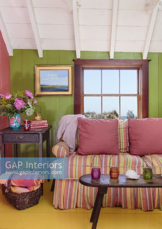 Le rembourrage à rayures bonbon du canapé fait écho aux manteaux de nombreuses couleurs qui traversent la maison.