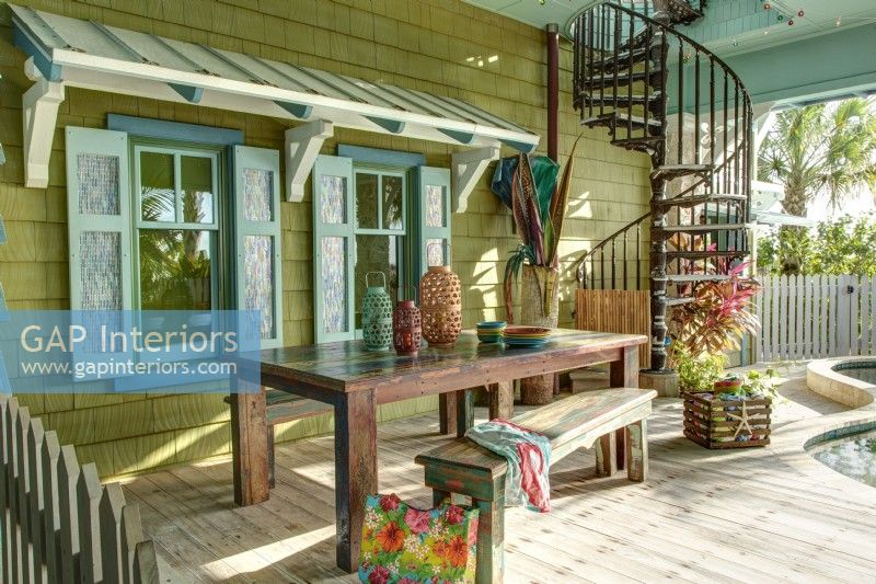 Un auvent en bois et des volets décoratifs donnent à la terrasse de la piscine une saveur caribéenne.