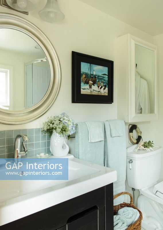 Des carreaux de dosseret en verre, une nouvelle vanité, un miroir rond - qui rappelle un hublot, rendent la salle de bain thermale jolie et confortable.