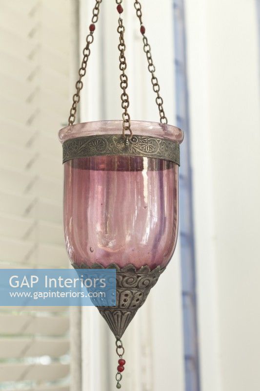 Une lanterne de style marocain équipée d'une bougie chauffe-plat attend que le crépuscule brille.