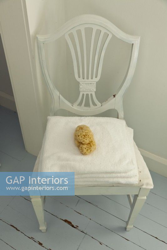 Une chaise vintage fait un endroit élégant pour les serviettes et une éponge naturelle