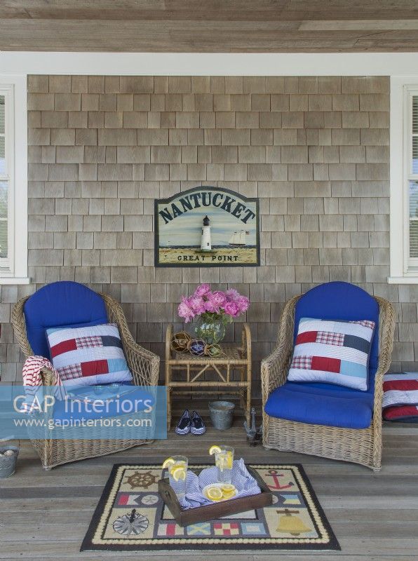 Des chaises en osier sur le porche accueillent les visiteurs. Les flotteurs de pêche en verre ajoutent une touche nautique.