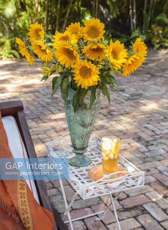 Une table de jardin permet de garder les boissons à portée de main. Symbole emblématique de la Toscane, les tournesols sont rassemblés dans un bouquet doré.