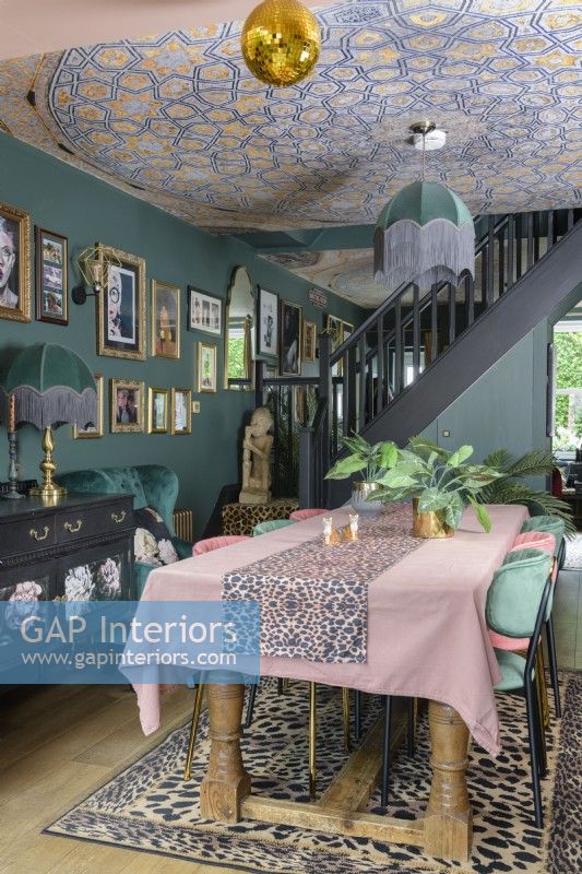 Coin repas ouvert vert foncé avec plafond tapissé de mosaïque et lampes de style art déco à franges