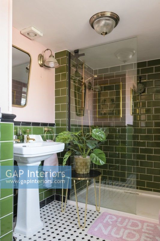 Blanc et lavabo et cabine de douche dans une salle de bains carrelée verte et rose pâle