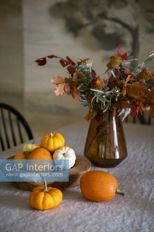 Affichage automnal de petites citrouilles et fleurs dans un vase sur la table