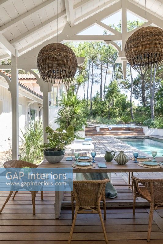 Covered outdoor dining area overlooking swimming pool and garden