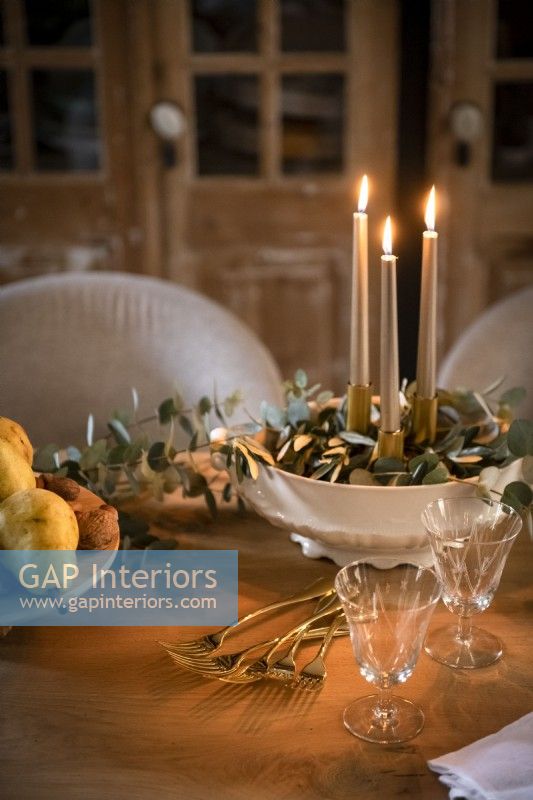 Bougies allumées dans un bol de feuillage décoratif sur la table à manger