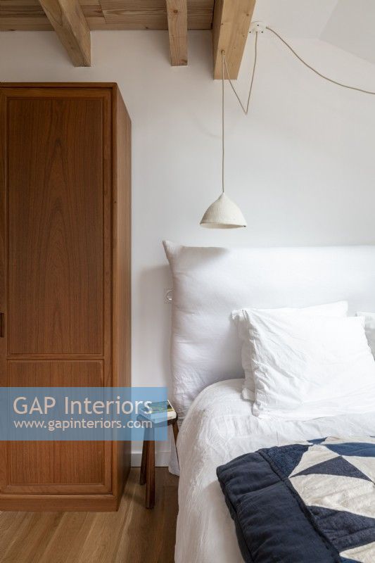 Chambre peinte en blanc avec armoire et parquet en bois