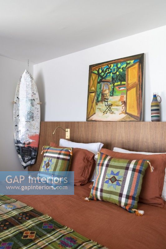 Planche de surf et œuvres d'art dans une chambre moderne avec literie à motifs