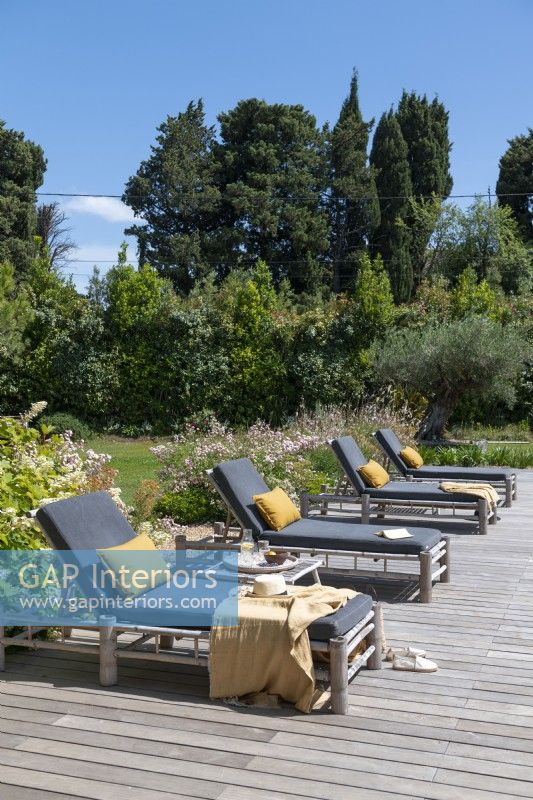 Coussins gris et jaunes sur des fauteuils inclinables sur une terrasse dans un jardin de campagne