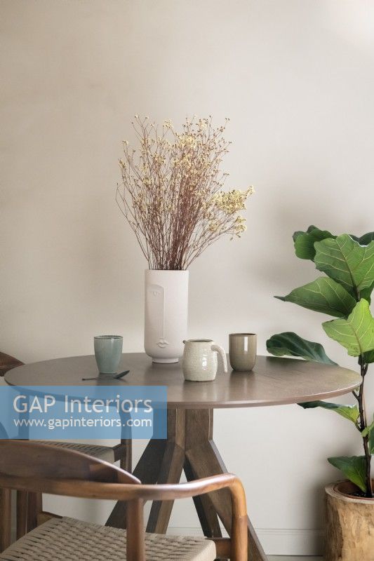 Vase en céramique de fleurs séchées sur une petite table en bois