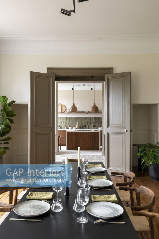 Salle à manger moderne avec vue sur la cuisine par des portes doubles