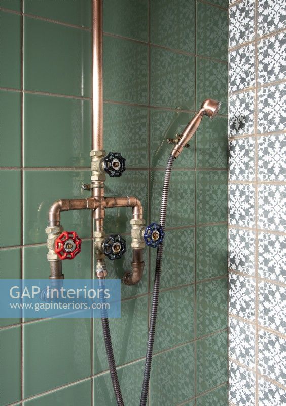 Détail des robinets et tuyaux de style industriel dans la cabine de douche